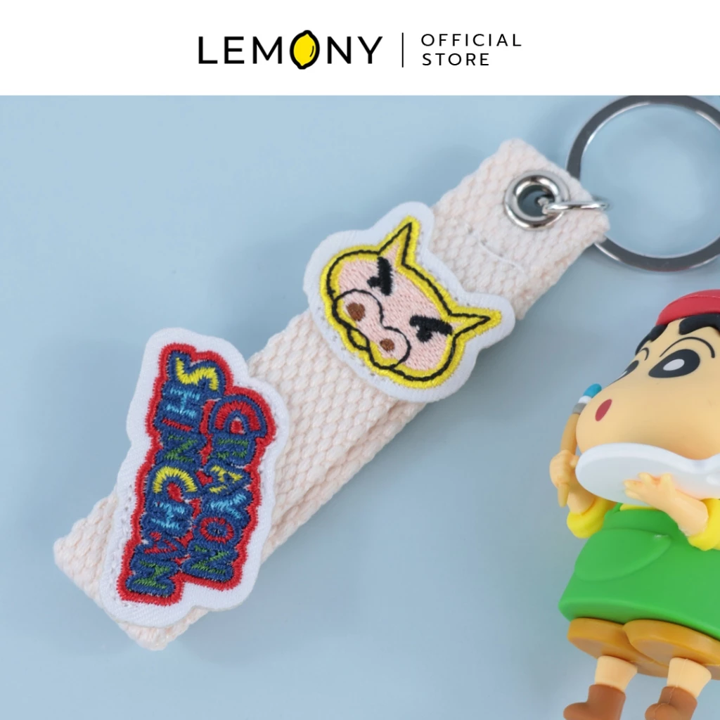 รายละเอียดงานปักบนสายคล้องผ้าพวงกุญแจ เป็นรูปหน้าบุริบุริซาเอมอนและโลโก้ Crayon Shin-chan สีสันสดใส