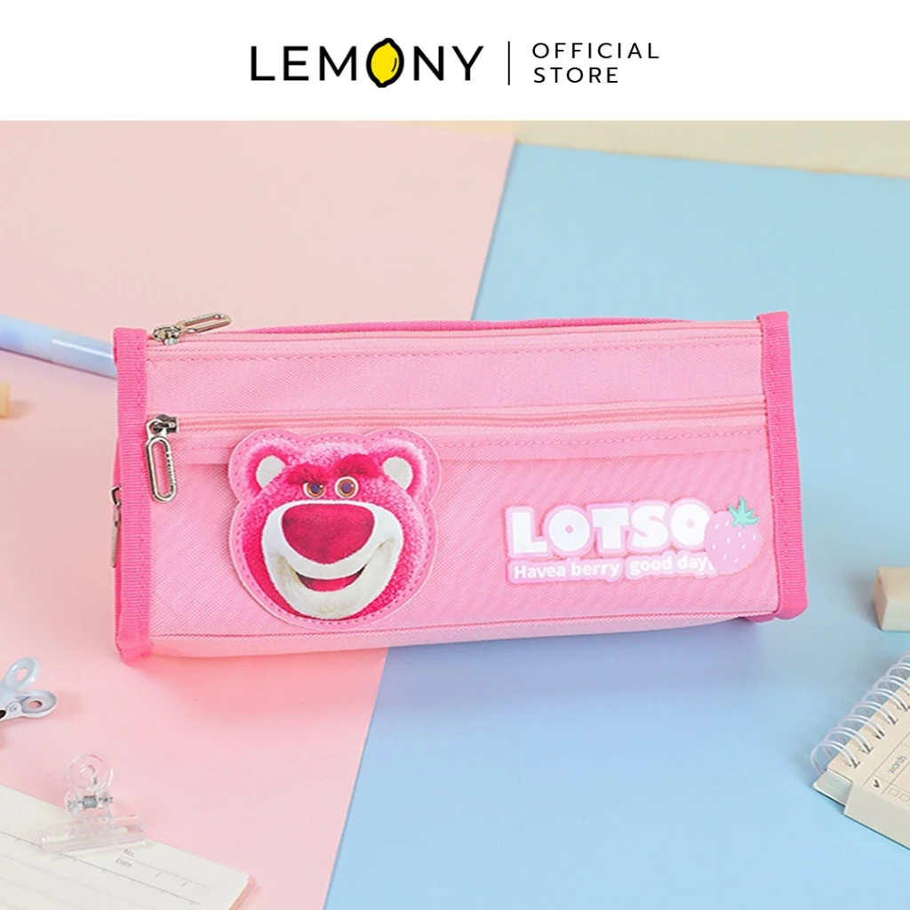 กระเป๋าดินสอ LEMONY ลายหมีล็อตโซ่ สีชมพูสดใส จัดวางในมุมเอียงบนพื้นหลังทูโทนสีชมพูและฟ้าพาสเทล รอบข้างประดับด้วยเครื่องเขียนน่ารัก เช่น สมุดโน้ตสันห่วงและคลิปหนีบกระดาษใส โดดเด่นด้วยงานปักหน้าหมี Lotso ตัวนูนและป้ายยาง LOTSO Have a berry good day แสนชิค