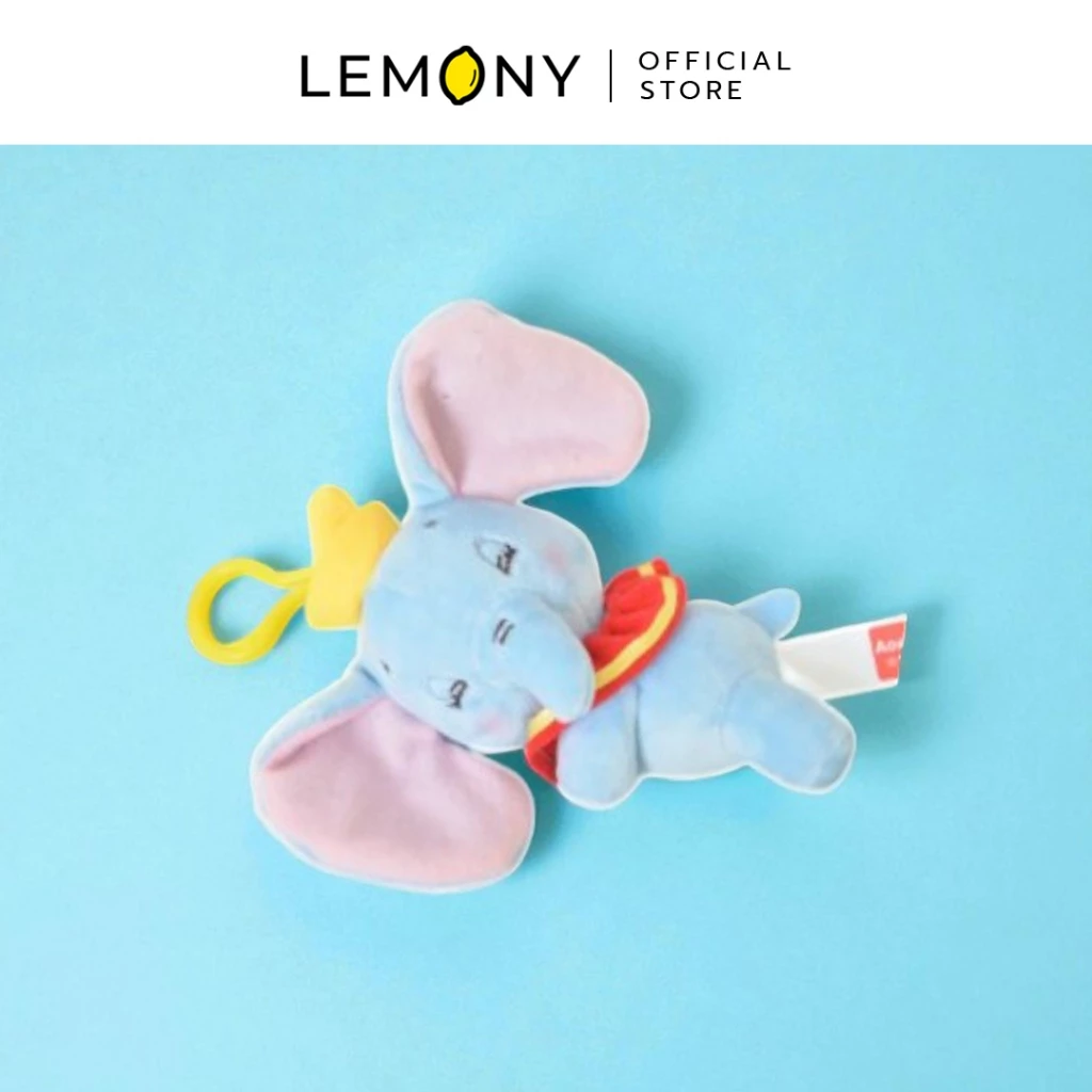 LEMONY พวงกุญแจตุ๊กตาดัมโบ้ ซีรีส์ Dream ขนาด 11 ซม. โชว์ดีไซน์ตุ๊กตาช้างน้อย Dumbo ตัวสีฟ้าพาสเทล หูตูบสีชมพูละมุนตากำลังนอนคว่ำหน้าหลับปุ๋ย รอบคอแต่งปกเสื้อระบายสีแดงขอบทอง สไตล์ละครสัตว์ มาพร้อมห่วงตะขอแขวนพลาสติกสีเหลืองสดใส จัดวางอยู่บนพื้นหลังสีฟ้าพาสเทล