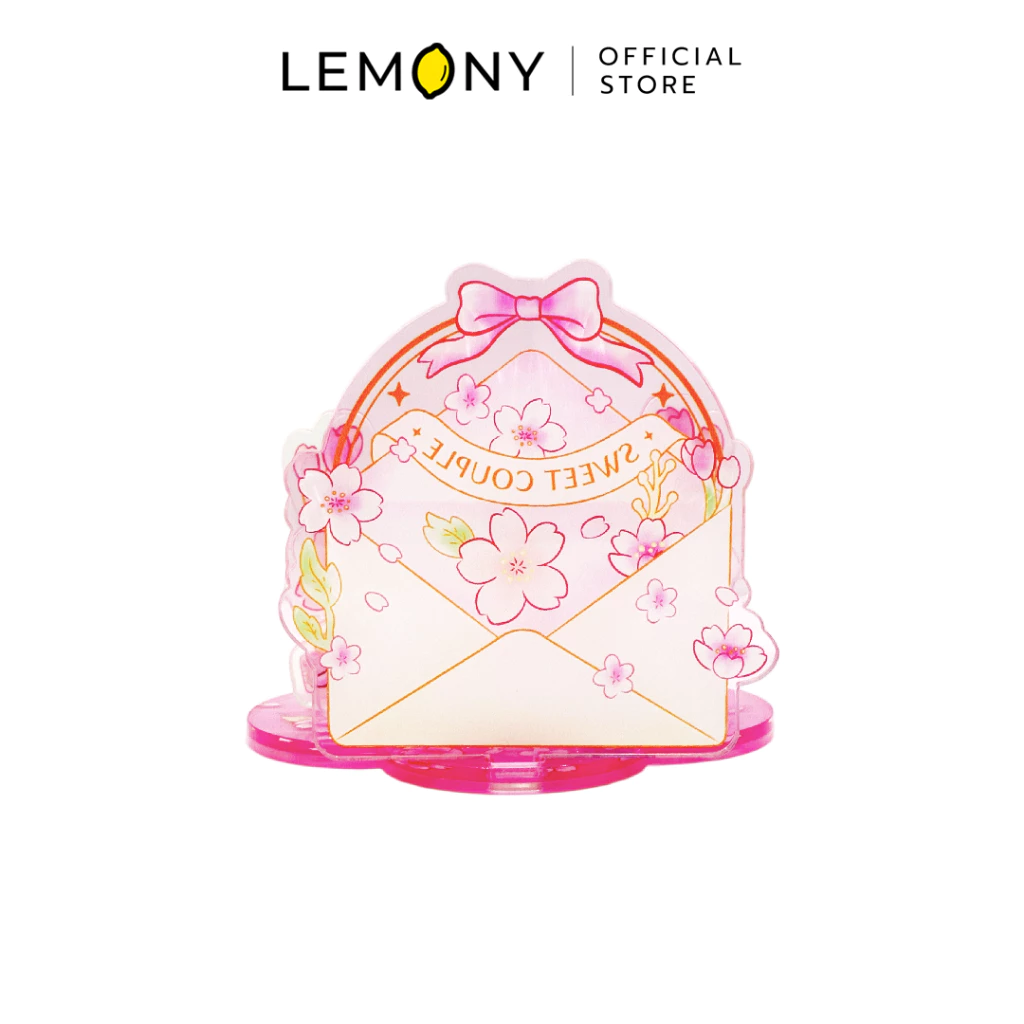 ภาพถ่ายด้านหลังของ LEMONY แท่นวางโทรศัพท์มือถืออะคริลิก ลายสติทช์และแองเจิล โชว์แผ่นอะคริลิกใสเลเยอร์หลังสุดที่เป็นรูปซองจดหมายสีชมพูอ่อนพิมพ์ลายดอกซากุระสะพรั่ง ผูกโบว์สีชมพูหวานและมีอักษรพิมพ์กลับด้านคำว่า SWEET COUPLE ตั้งอยู่บนฐานทรงกลีบดอกไม้