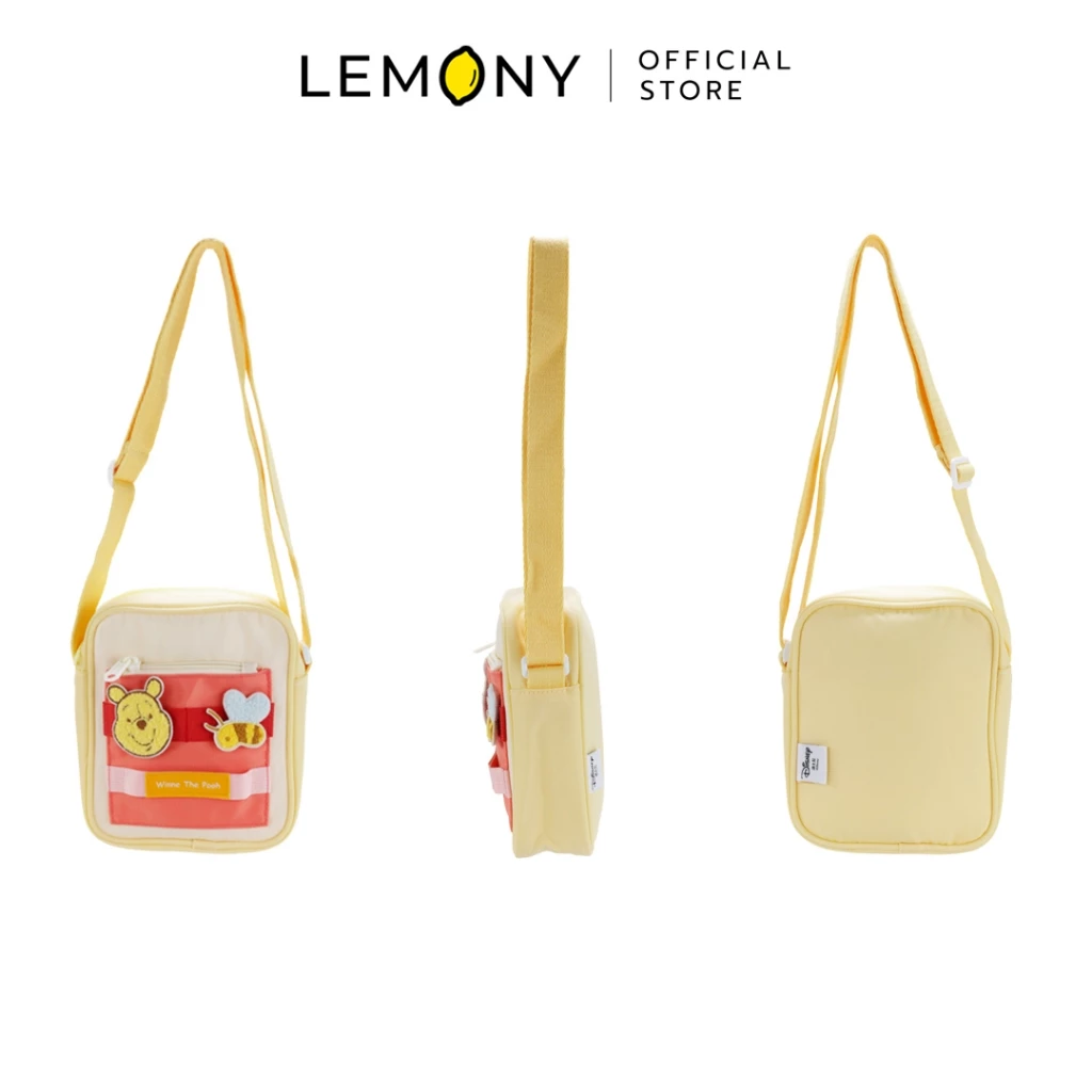 ภาพสินค้าฉากหลังขาวแสดงมุมมอง 3 ด้านของกระเป๋าสะพายข้างดิสนีย์ ซีรีส์ Candy ลายวินนี่เดอะพูห์ (Winnie the Pooh) ตัวกระเป๋าผ้าสีเหลืองพาสเทล ด้านซ้ายโชว์มุมหน้าตรงปักลายหมีพูห์คู่กับตัวผึ้งจิ๋วบนช่องซิปหน้าสีชมพูสลับส้ม มีป้ายคำว่า Winnie the Pooh มุมกลางโชว์ด้านข้าง และด้านขวาโชว์มุมหลังเรียบ มีสายสะพายยาวสีเหลืองเข้าเซ็ต ด้านบนระบุโลโก้แบรนด์ LEMONY Official Store