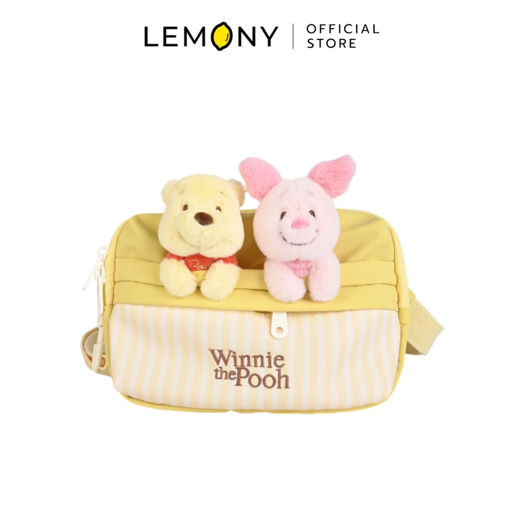 LEMONY กระเป๋าคาดอกดิสนีย์ ลาย Winnie the Pooh ทรงกล่องสี่เหลี่ยมผืนผ้าสีเหลืองพาสเทลสลับลายทางแนวตั้งสีขาว มีช่องซิปด้านหน้าปักอักษรชื่อเรื่อง โดดเด่นด้วยตุ๊กตาหัวนูนสามมิติดีไซน์หมีพูห์และพิกเล็ตเกาะอยู่บนขอบกระเป๋าอย่างน่ารัก