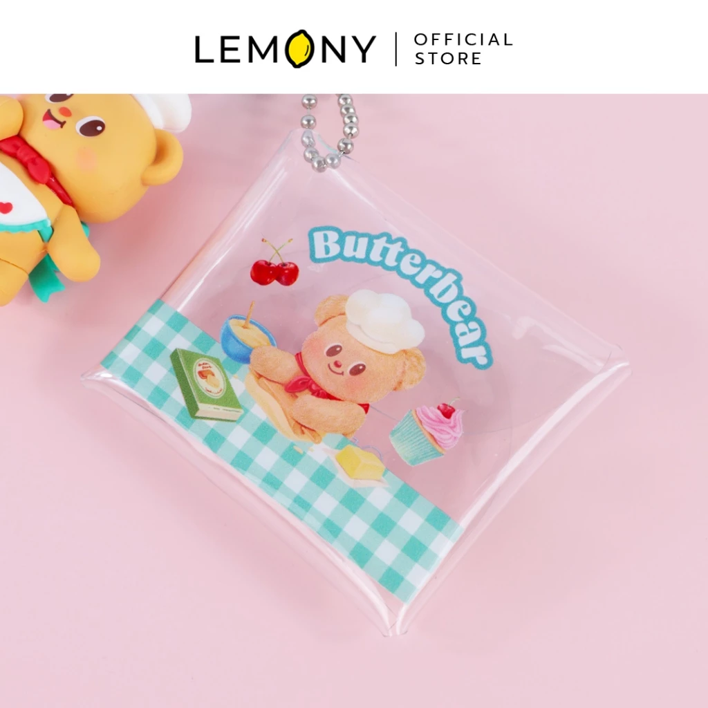 ภาพถ่ายระยะใกล้ โฟกัสลายสกรีนคมชัดบนซองกระเป๋าพลาสติกใส ลายหมีเนย Butterbear สวมหมวกเชฟทำขนม ตกแต่งลายสก็อตสีฟ้ามิ้นต์ เชอร์รี่ และคัพเค้ก พร้อมข้อความ Butterbear โทนสีพาสเทลน่ารัก ฉากหลังสีชมพูละมุน ด้านบนสุดระบุโลโก้แบรนด์ LEMONY Official Store