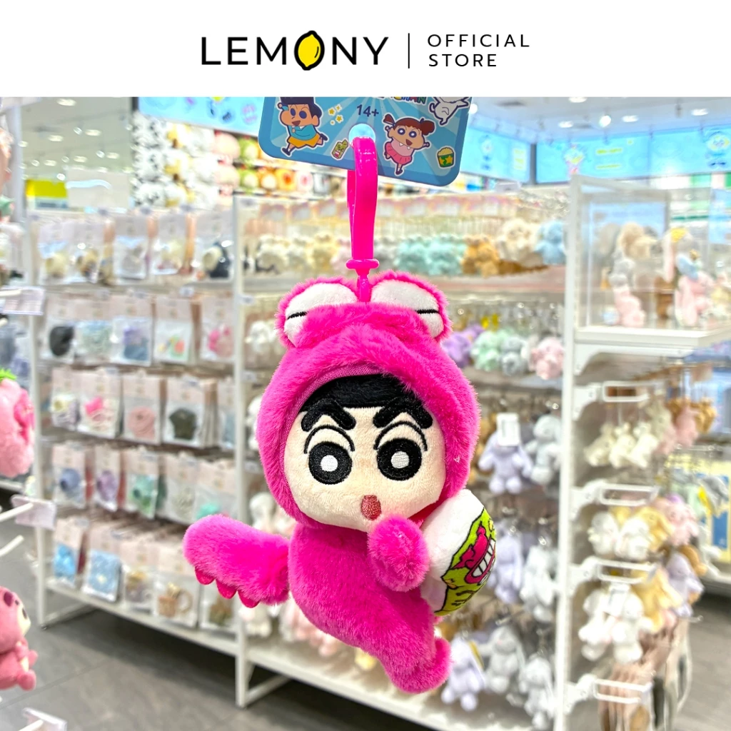 ภาพถ่ายสินค้าจริงในร้านค้า เผยพวงกุญแจตุ๊กตาชินจังสุดคิ้วท์คอสเพลย์ชุดไดโนเสาร์สีชมพูช็อกโกบีขนนุ่มฟูละเอียด กำลังแขวนโชว์หน้าตรงด้วยห่วงล็อกพลาสติกสีชมพูเข้มเข้าชุด แขนข้างหนึ่งโอบกอดขนมช็อกโกบีจำลอง ฉากหลังเผยชั้นวางของและสินค้าบิวตี้ไอเทมจัดวางเรียบร้อย ด้านบนระบุตราสัญลักษณ์ร้านค้า LEMONY Official Store
