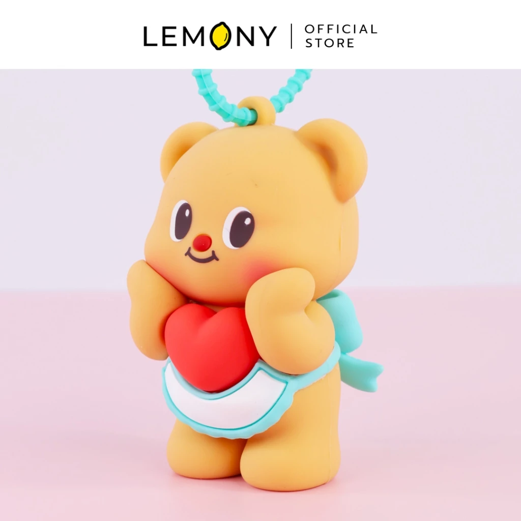 ภาพถ่ายซูมหน้าตรงระยะใกล้ของพวงกุญแจซิลิโชกน้องหมีเนย Butterbear ตาโตแก้มชมพูอมส้ม สวมผ้ากันเปื้อนสีขาวขอบฟ้า สองมือยกอุ้มดวงใจสีแดงดวงโต พร้อมสายห้อยซิลิโคนล็อกสีฟ้ามิ้นต์ด้านบน ฉากหลังสีชมพูหวานละมุน ด้านบนสุดระบุโลโก้แบรนด์ LEMONY Official Store